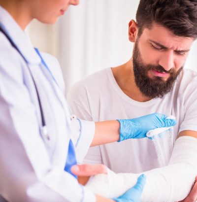 Injury hands. Young man with injured hands. Young woman doctor helps the patient